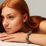 Model wearing Signature Polished Gold Earrings by Märta Larsson with chunky bracelet and relaxed pose. Gold stud earrings styled for effortless cool and Swedish minimalism.