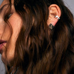 Model wearing Mondrian Stud Earrings Dalmatian by Märta Larsson with silver ear cuff and speckled stud. Dalmatian earrings styled for minimalist edge and artistic flair.