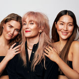 Three people standing together, with Märta Larsson in the center wearing a gold collar necklace.