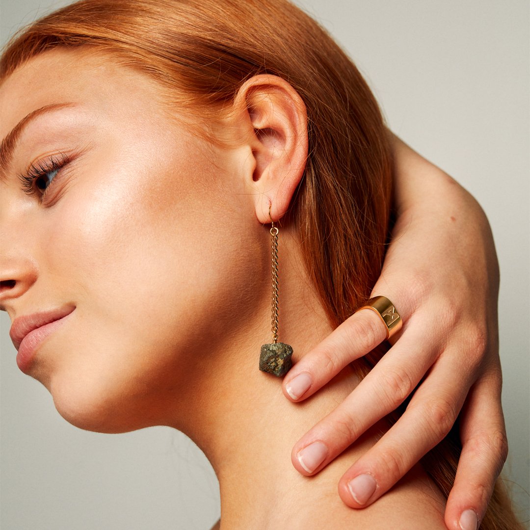 Model brushing hair from her neck, wearing the Signature Gold Vermeil Ring by Märta Larsson on the pinky finger. This minimalist gold ring adds elegance and edge to casual styling.
