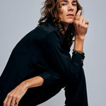 Male model posing against a grey background wearing the Black Tourmaline Ring by Märta Larsson on his pinky finger. This gold tourmaline ring is a sculptural piece of wearable art, ideal for lovers of brutalist rings and Swedish jewelry.