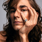 Close-up of a male model wearing the Black Tourmaline Ring by Märta Larsson on his pinky finger, photographed near his face. This black tourmaline gold ring is a refined yet edgy accessory for crystal lovers and modern ring collectors.