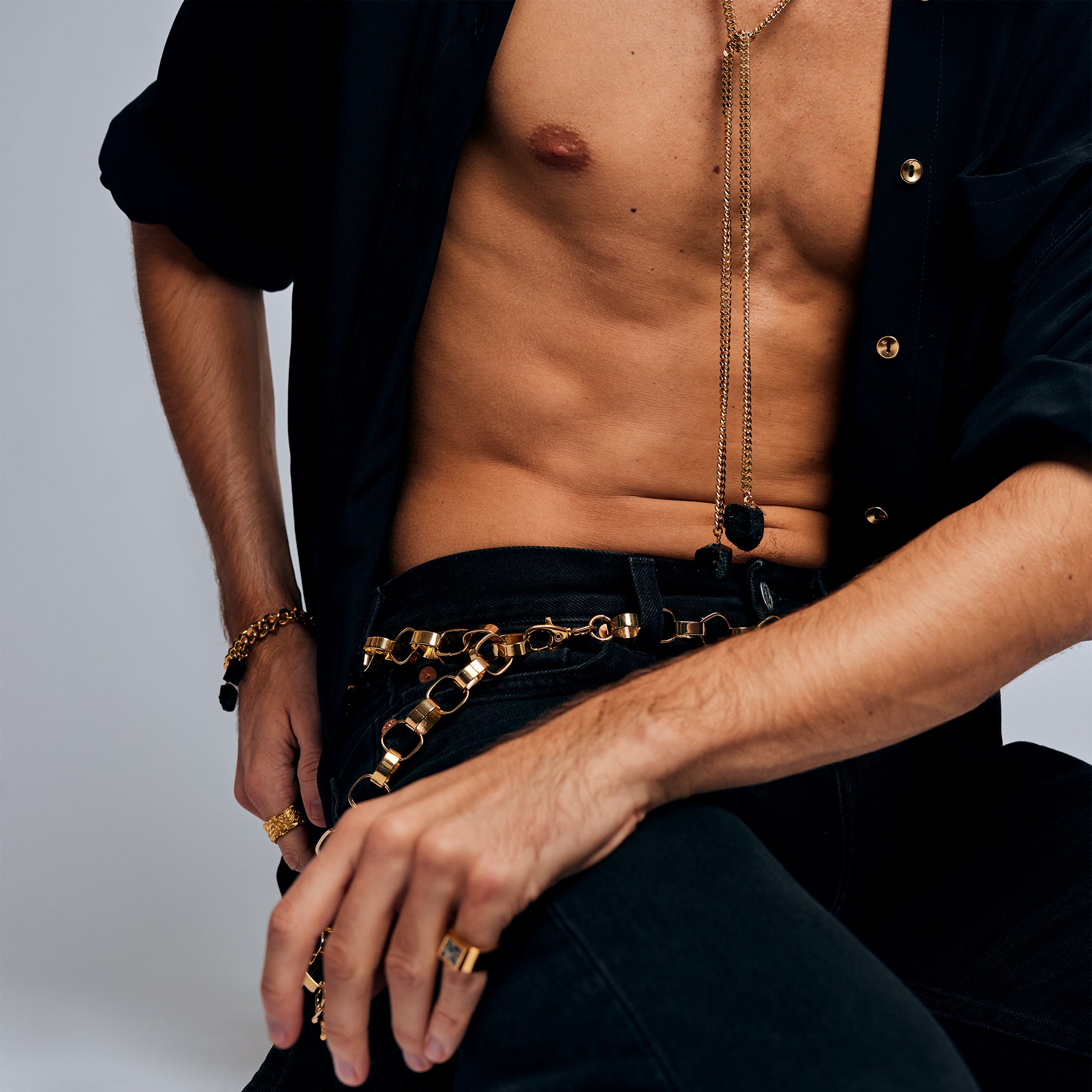 Model in black outfit with gold accessories wearing the Mondrian Ring Dalmatian by Märta Larsson. Statement ring styled with chain belt and layered bracelets.