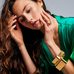 Female model with hands near her face wearing the Shattuckite Signet Ring by Märta Larsson on her ring finger. This designer crystal ring adds a refined touch to any outfit, perfect for fashion-forward styling and artistic expression.