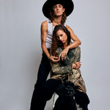 Two models embracing, with the male model wearing the Shattuckite Signet Ring by Märta Larsson on his pinky finger. This bold gemstone ring is a gender-neutral accessory that adds visual impact to any outfit.