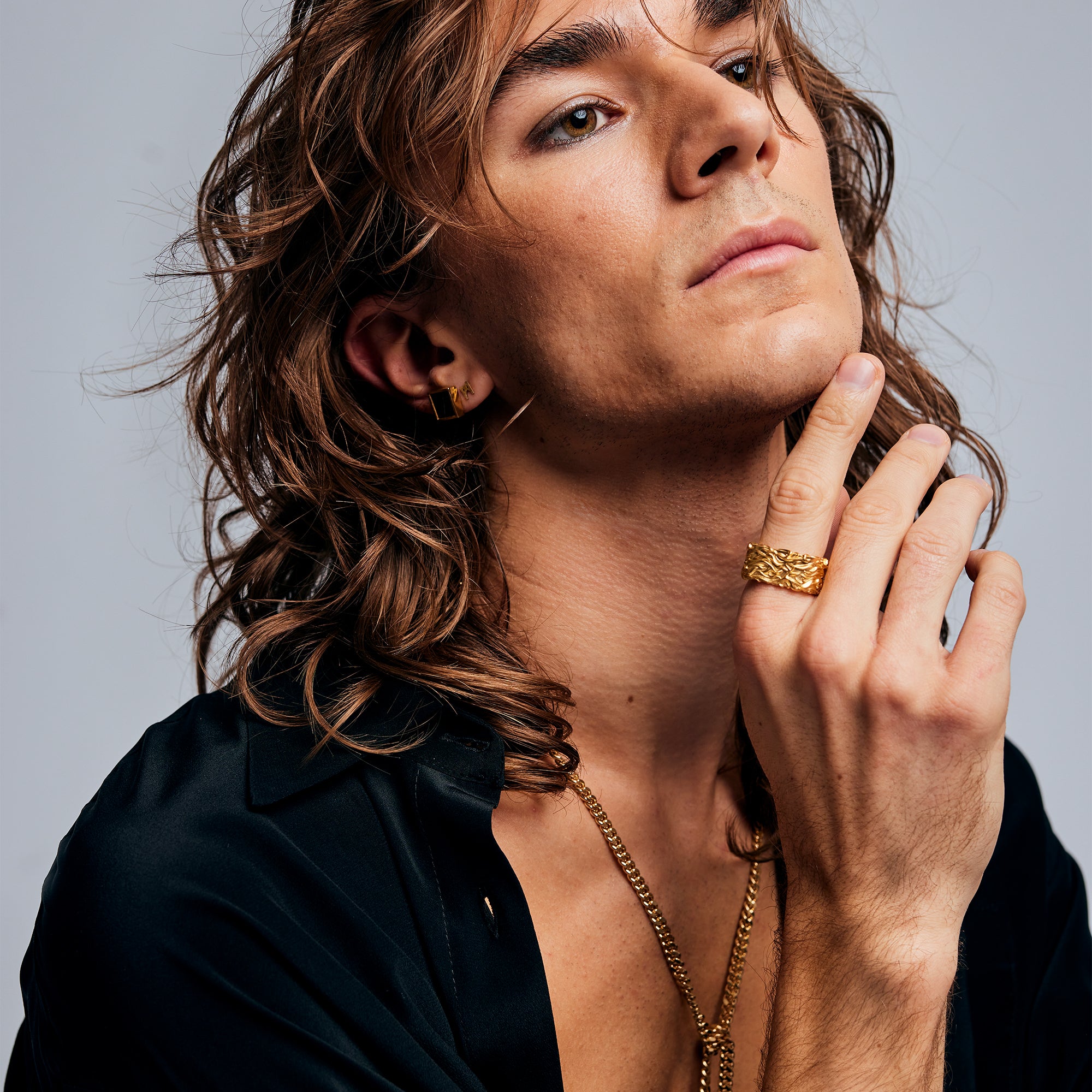 Portrait of male model wearing Ring of Fire Gold by Märta Larsson on index finger. Clean, powerful gold ring with flame motif.