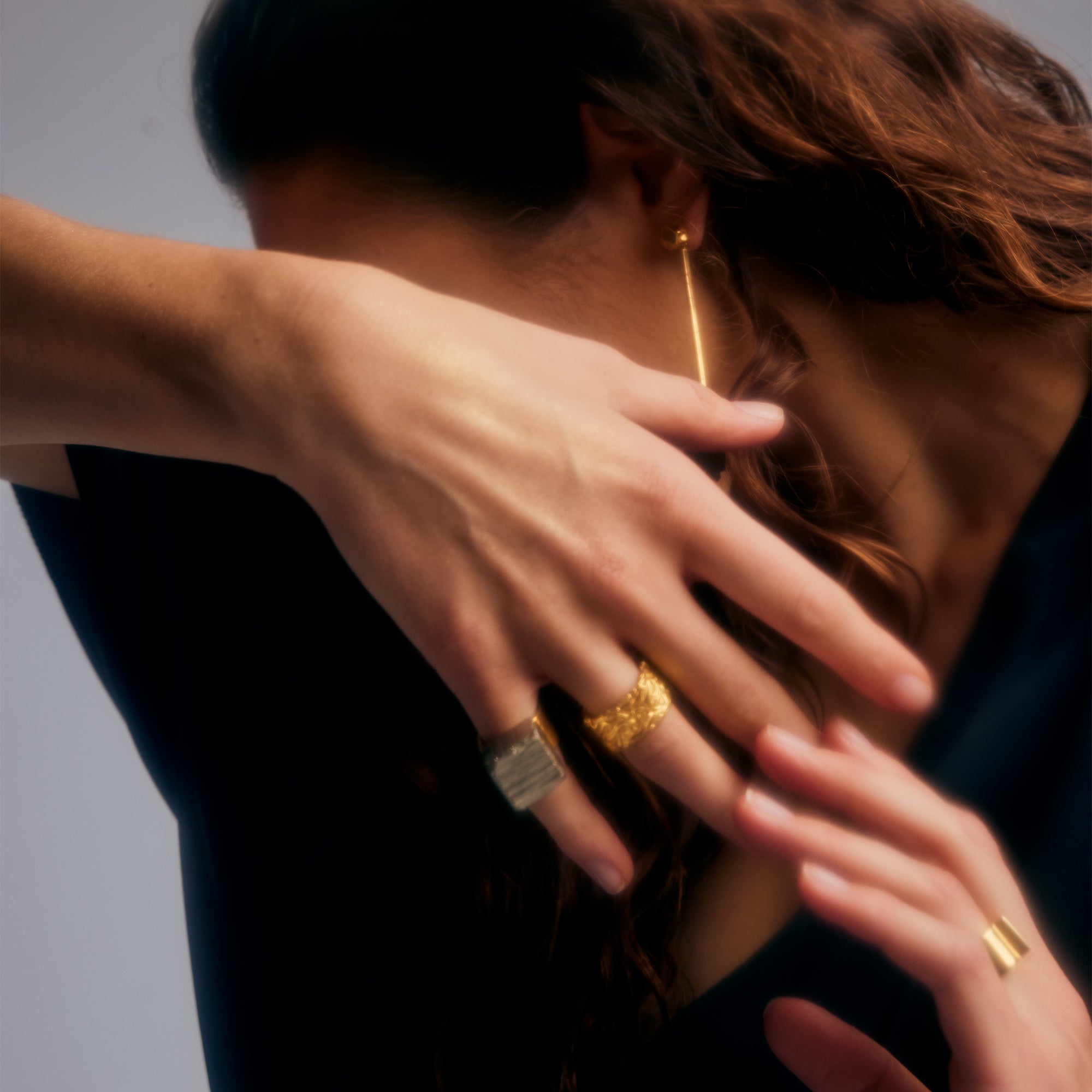 Female model with hand over face, wearing Ring of Fire Gold by Märta Larsson on ring finger. Artistic gold ring with bold silhouette.