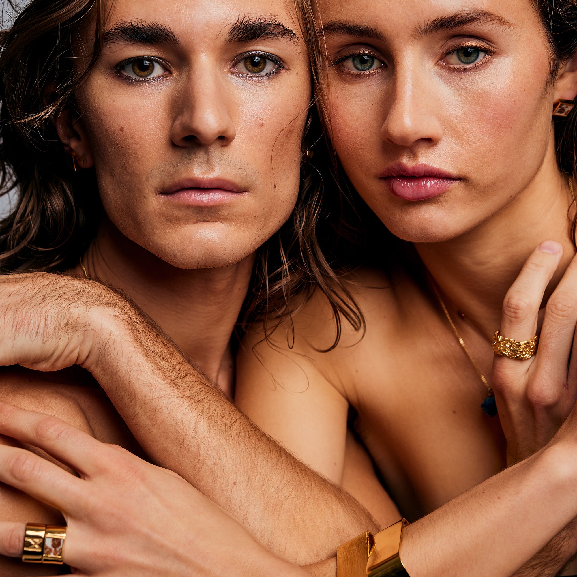 Two models looking into camera, male wearing Ring of Fire Gold by Märta Larsson on pinky. Bold designer ring with flame-inspired design.