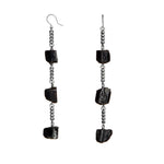 Longing Black Tourmaline Earrings by Märta Larsson with silver-toned chain and raw black stones. Statement earrings — handcrafted and naturally powerful.