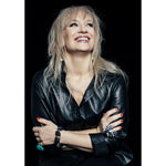 Model smiling in black outfit wearing Art Ring Special Edition Quartz by Märta Larsson. Clear quartz ring styled with red nails and layered bracelets — joyful and bold fashion look.