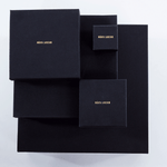 Luxury packaging for Märta Larsson jewelry, black boxes with gold branding designed for pyrite rings and crystal accessories.