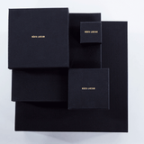 Luxury packaging for Märta Larsson jewelry, black boxes with gold branding designed for pyrite rings and crystal accessories.