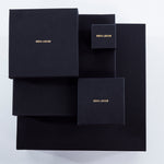 Collection of black jewelry boxes with gold Märta Larsson branding. Elegant packaging for handcrafted gemstone rings and luxury accessories.