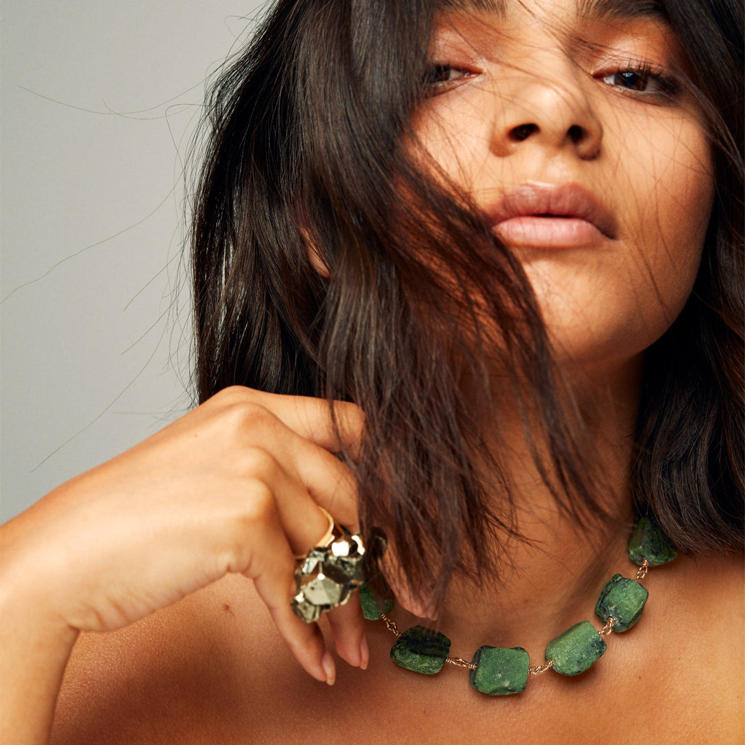 Model wearing Roxx Pyrite Crystal Ring by Märta Larsson on index finger. Pyrite crystal ring styled with tousled hair and sculptural necklace — perfect for brutalist fashion.