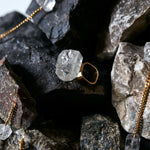 Close-up of quartz ring placed among dark rocks. Roxx Quartz Ring by Märta Larsson with faceted gemstone — contrast between raw nature and refined luxury.