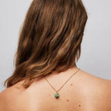 Brown hair woman with her hair swept to one side, showcasing The Raw One Necklace by Märta Larsson with the gold chain and ruby zoisite stone hanging down her spine.