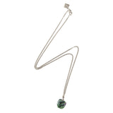 Silver chain necklace with a raw ruby zoisite stone, arranged in a lightning-like shape on a white background.