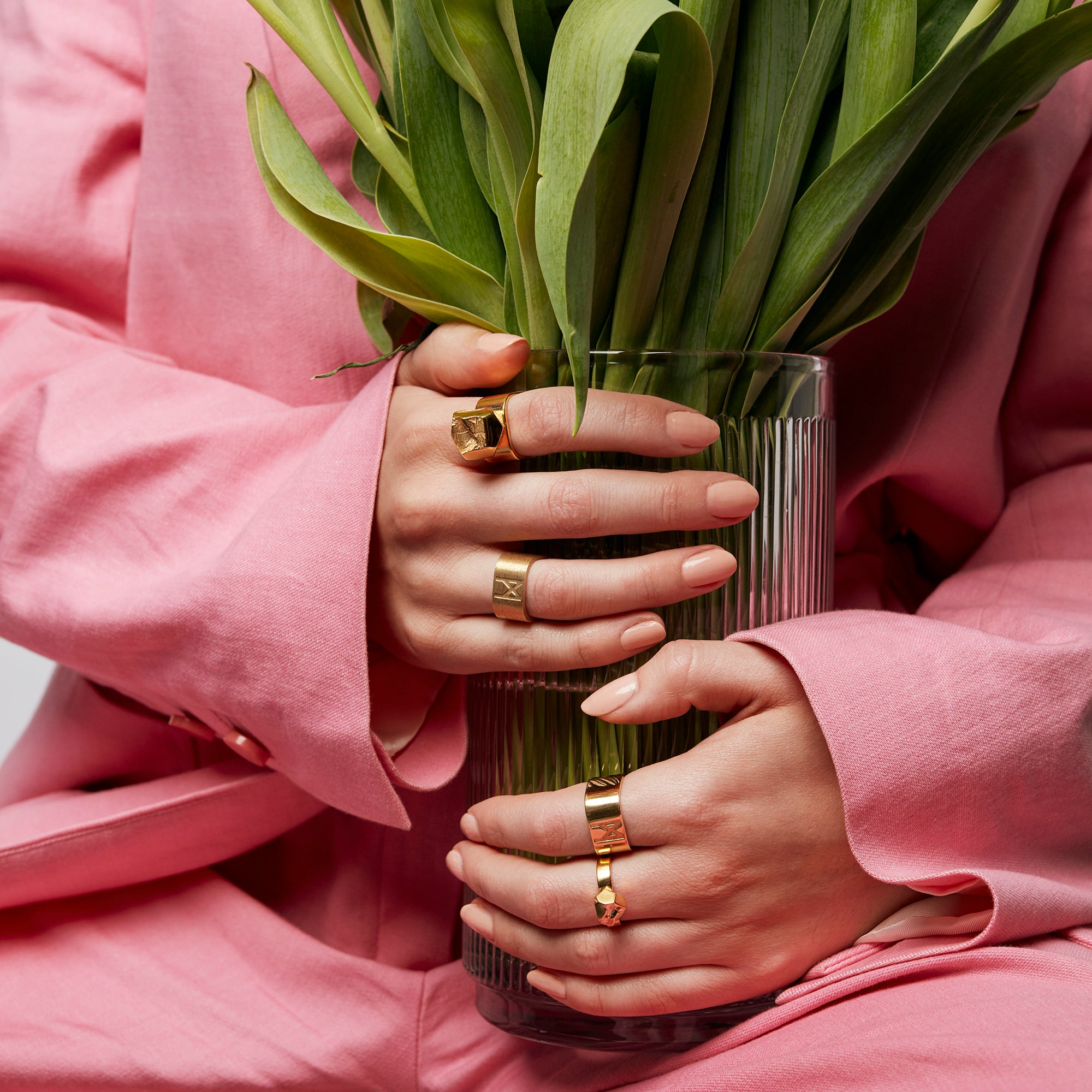 Two hands holding a vase, one wearing The Billie Ring by Märta Larsson on the middle finger. The gold vermeil and raw crystal design make this handcrafted ring a timeless piece in Swedish jewelry craftsmanship.