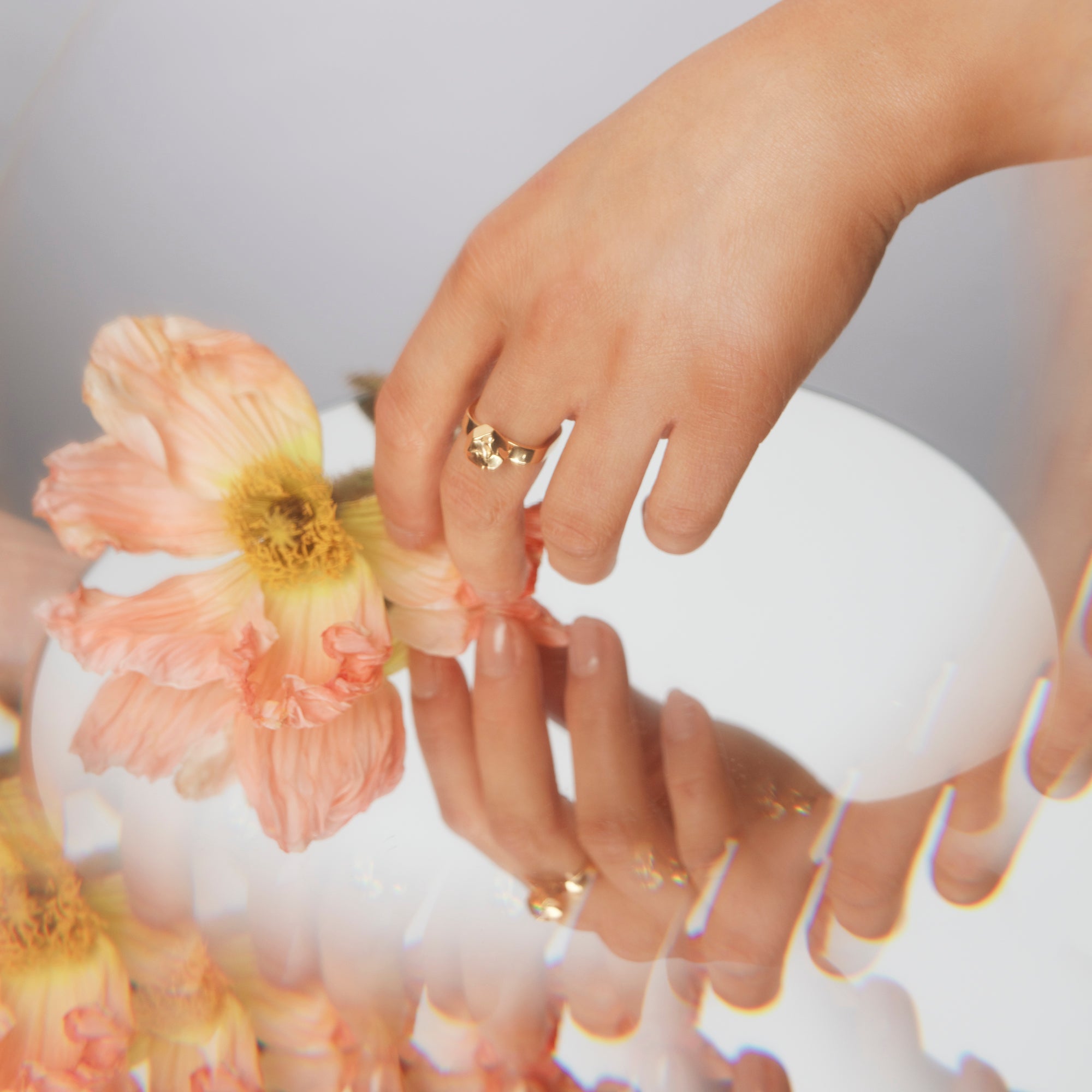 Hand reaching for a flower above a mirror, wearing The Billie Ring by Märta Larsson on the middle finger. This raw stone ring captures nature’s untamed beauty in precious metal — a poetic touch to any outfit.