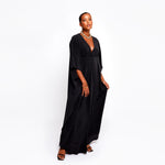 Model wearing luxury designer black kaftan dress in flowing silk, flattering relaxed fit.