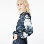 Side view of a model wearing the Glam Rock Silk Satin Shirt Dress by Märta Larsson. The shirt’s fluid drape and waist tie offer a flattering fit for all body shapes, making it a standout designer shirt dress in luxury womenswear.