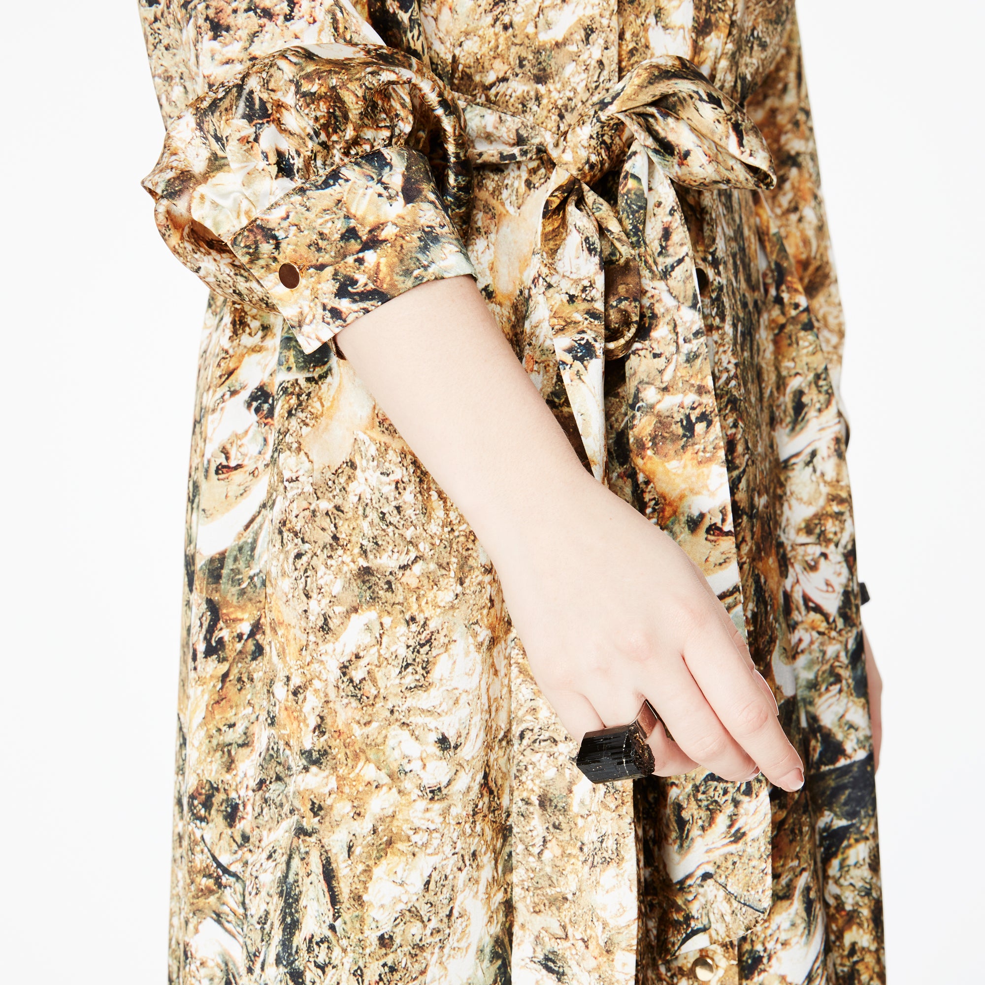 Close-up of the side of the Glam Rock Silk Satin Shirt Dress by Märta Larsson, showing the fabric’s pattern and model’s hand. The silk satin texture and subtle detailing highlight the elegance of this designer shirt dress, ideal for fashion-forward women.