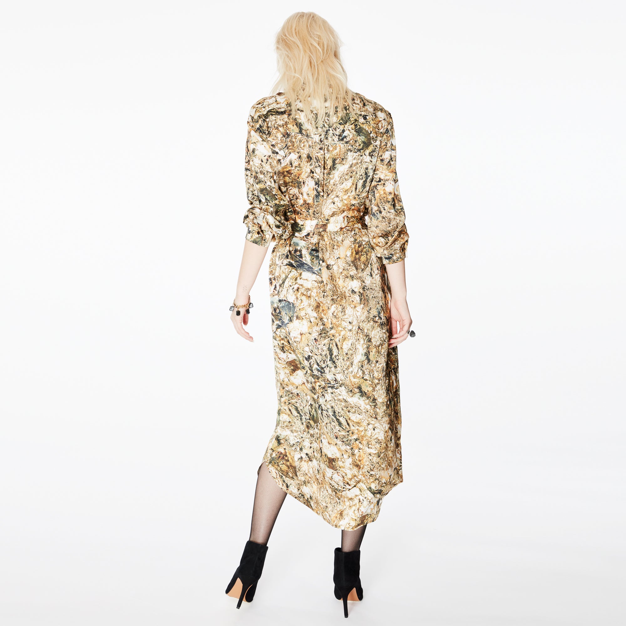 Back view of a model wearing the Glam Rock Silk Satin Shirt Dress by Märta Larsson. The dropped hem and back pleats create a sculptural silhouette, ideal for pairing with fashion accessories or styling as an elegant silk dress.