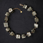 Not A Pearl Necklace Pyrite by Märta Larsson laid out on black textured surface. Gold necklace with raw pyrite stones — handcrafted and sculptural.
