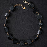 Not A Pearl Necklace Black Tourmaline by Märta Larsson laid out on black textured surface. Gold necklace with black tourmaline stones — handcrafted and sculptural.