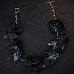 Not A Pearl Necklace XXL Black Tourmaline Crystal by Märta Larsson laid out on black textured surface. Gold necklace with large black tourmaline crystals — handcrafted and sculptural.