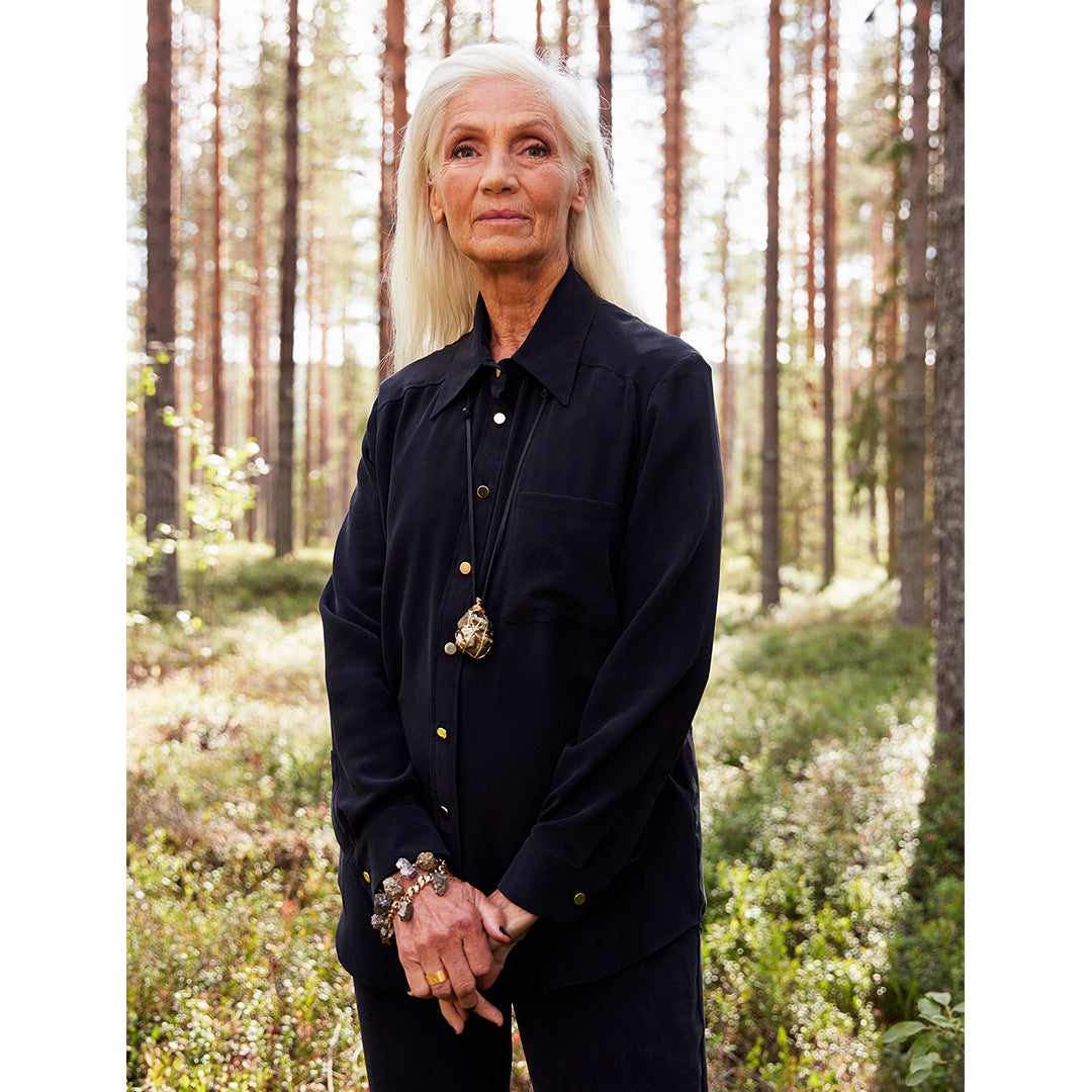 Model wearing the Boyfriend Silk Shirt by Märta Larsson in a forest setting. The relaxed-fit shirt in 100% sand-washed silk features a drop hem back and boyish collar, offering a laid-back luxury look perfect for pairing with mens fashion jewelry or designer mens jewellery.
