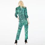 Back view of a model wearing the Boyfriend Silk Satin Shirt by Märta Larsson, posing against a green background. The drop hem and clean lines make this silk shirt a versatile choice for contemporary womens fashion and designer wardrobe essentials.
