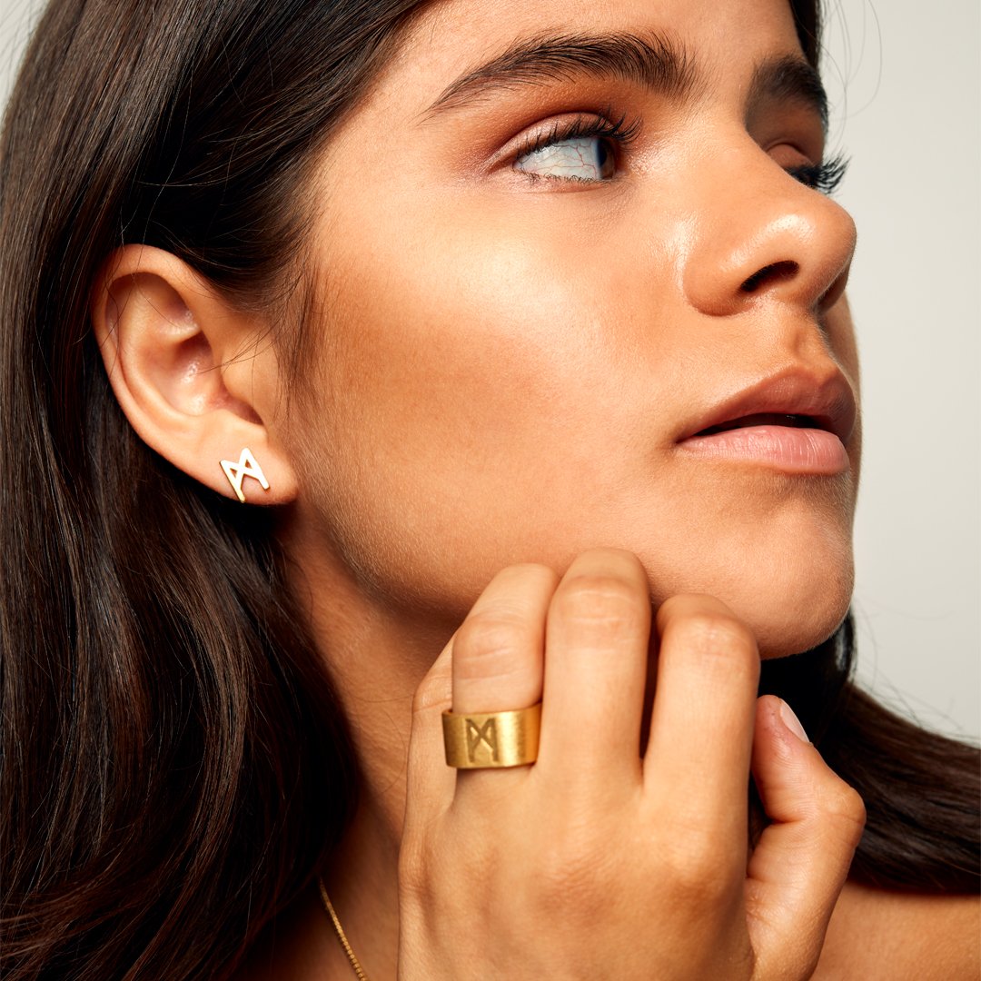 Close-up of a brown-haired model wearing the Signature Brushed Gold Ring by Märta Larsson in brushed 24 carat gold vermeil with wide matte band.