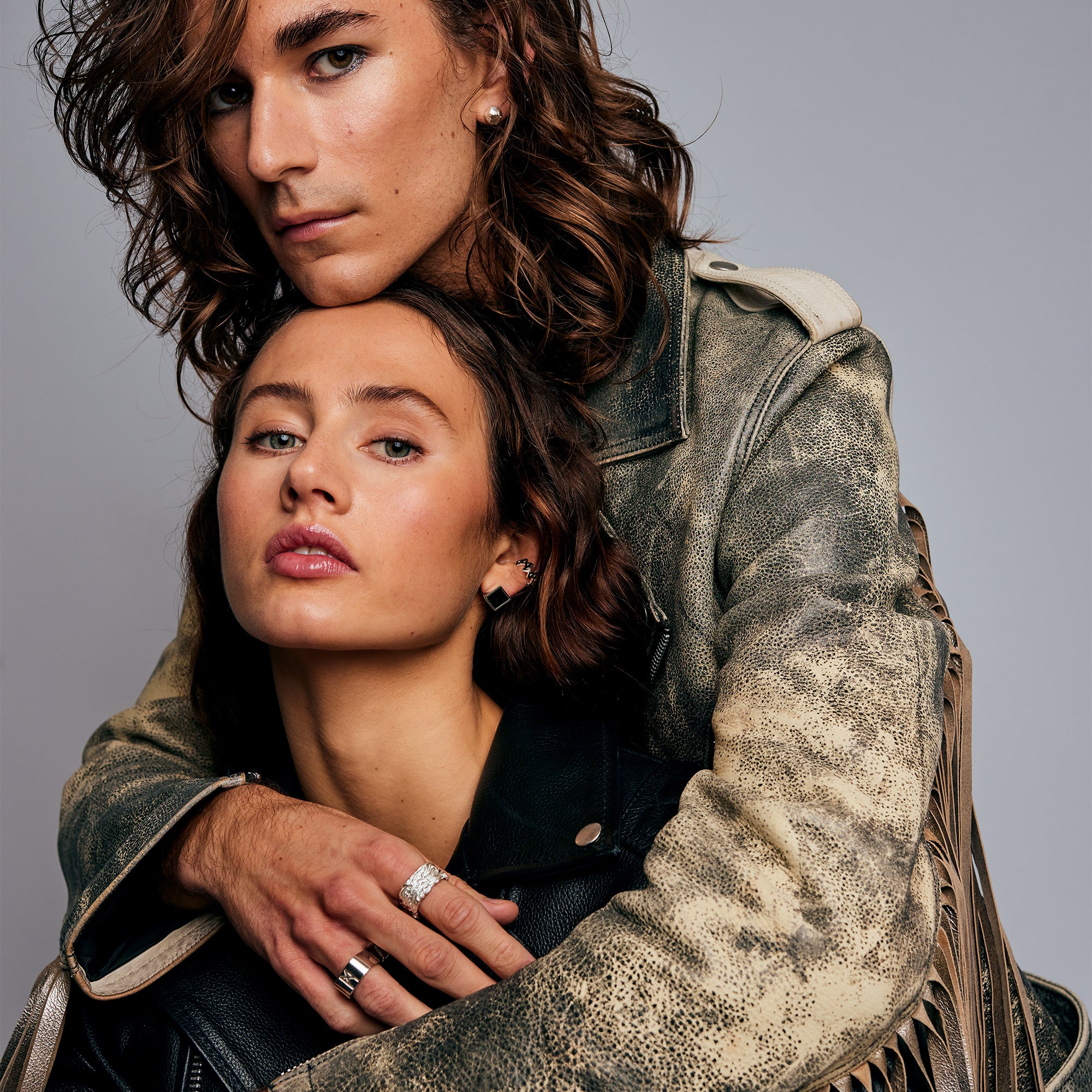 Two models embracing, with the male model wearing the Signature Silver Ring by Märta Larsson on the ring finger. The clean design and engraved detail make this polished silver ring a versatile statement piece.      