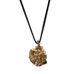 Close-up of Bondage Pyrite Gold Pendant Necklace by Märta Larsson with rugged crystal and wire cage. Raw pyrite necklace styled for punk attitude and natural edge.