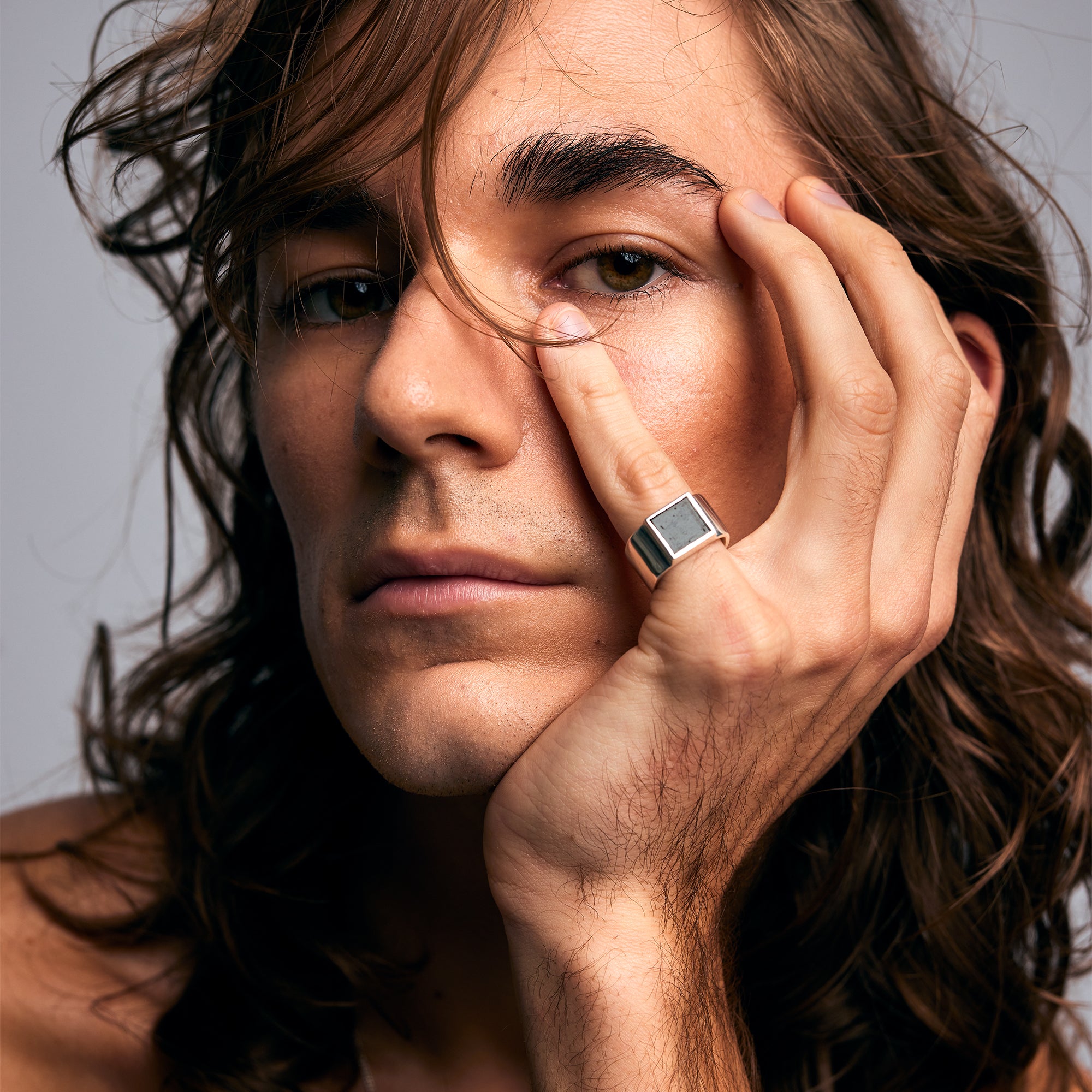Close-up of a male model wearing the Black Tourmaline Ring by Märta Larsson on his pinky finger, photographed near his face. This black tourmaline gold ring is a refined yet edgy accessory for crystal lovers and modern ring collectors.
