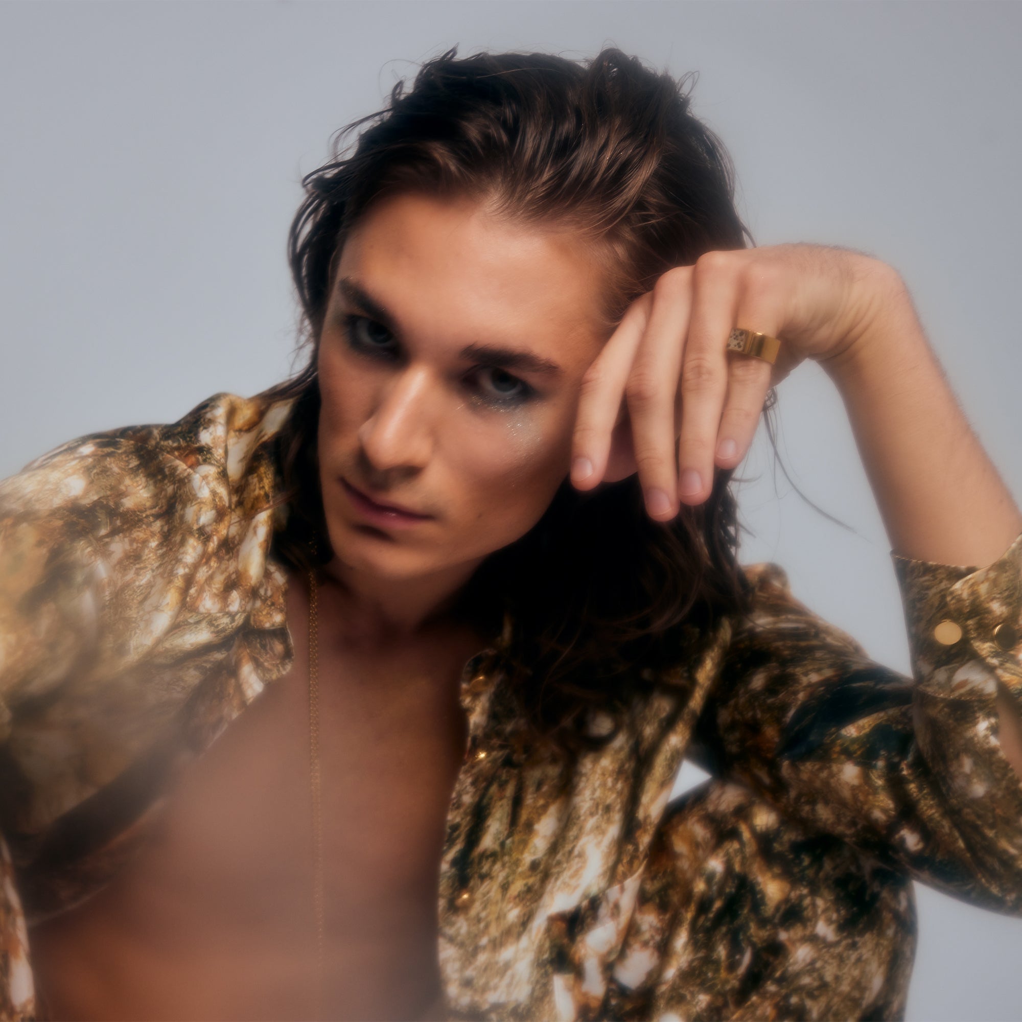 Model wearing the Mondrian Ring Dalmatian by Märta Larsson on the index finger, styled with patterned shirt and necklace. Artistic gemstone ring with bold geometric design.
