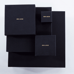  Collection of black jewelry boxes with gold Märta Larsson branding. Elegant packaging for handcrafted gemstone rings and luxury accessories.