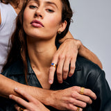 Close-up of two individuals, one wearing the Mondrian Ring Lapis Lazuli by Märta Larsson on index finger. Gold ring with lapis lazuli styled with leather and layered jewelry.
