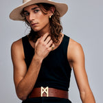 Model in beige hat and black top wearing the Mondrian Ring Ruby Zoisite by Märta Larsson. Gold jewelry styled with rune-like belt buckle and square ear cuff.