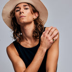 Model in wide-brimmed hat wearing the Mondrian Ring Ruby Zoisite by Märta Larsson on the ring finger. Gold vermeil ring with natural stone, styled with bold accessories and confident pose.
