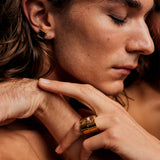 Close-up of a person with eyes closed wearing the Mondrian Ring Garnet in Limestone by Märta Larsson on the index finger, a bold gold-vermeil natural stone ring styled with a matching earring.
