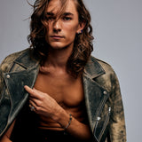 Model in distressed leather jacket wearing the Mondrian Ring Garnet in Limestone by Märta Larsson on the pinky, a rugged yet refined gold-vermeil art ring