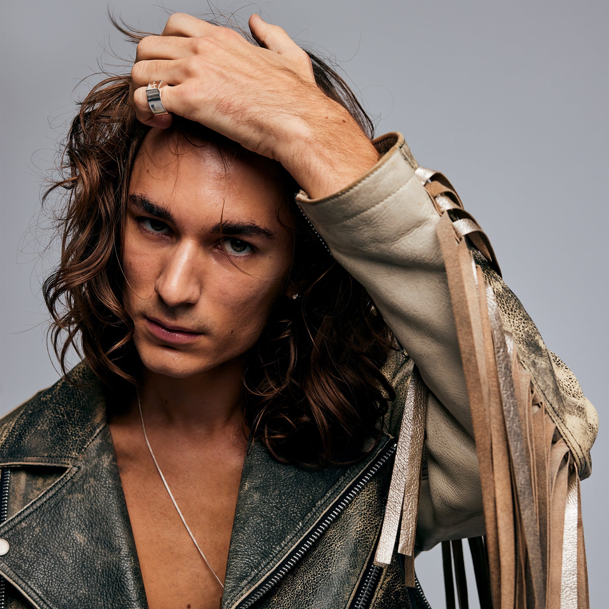 Model in fringe leather jacket holding hair back wearing the Mondrian Ring Garnet in Limestone by Märta Larsson, an edgy handcrafted Swedish jewelry piece.