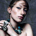 Close-up portrait of model wearing Not A Pearl Necklace Chrysocolla by Märta Larsson, a chunky raw chrysocolla statement piece styled with bold mineral ring.