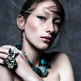 Close-up portrait of model wearing Not A Pearl Necklace Chrysocolla by Märta Larsson, a chunky raw chrysocolla statement piece styled with bold mineral ring.