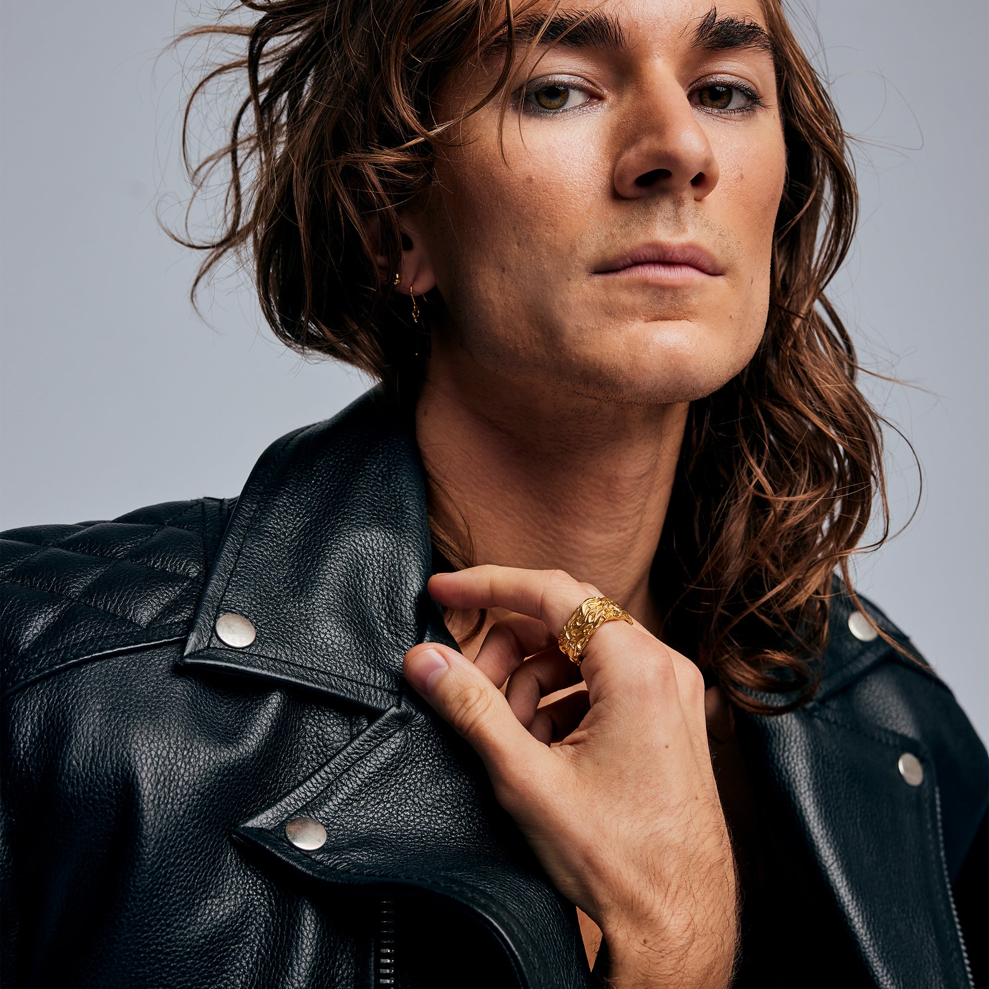 Male model in leather jacket wearing the Ring of Fire Gold by Märta Larsson on the index finger, a rock-inspired gold-vermeil ring with sculptural edge.