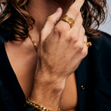 Male hand wearing the Ring of Fire Gold by Märta Larsson on the index finger, a brutalist gold-vermeil ring with square sculptural silhouette.
