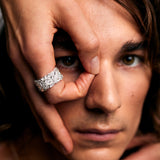Close-up of a male model making an “O” gesture around his eye, wearing the Ring of Fire Recycled Sterling Silver by Märta Larsson with bold 11 mm flame-detailed band.