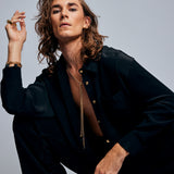 Model wearing the Tie Me Up Black Tourmaline Necklace by Märta Larsson, a raw tourmaline lariat styled with layered gold jewelry for confident elegance.